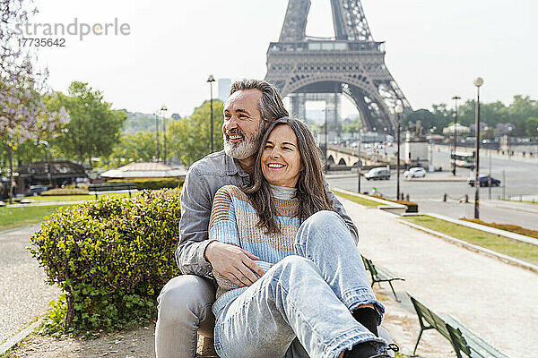 Fröhlicher reifer Mann und Frau sitzen zusammen im Park vor dem Eiffelturm  Paris  Frankreich