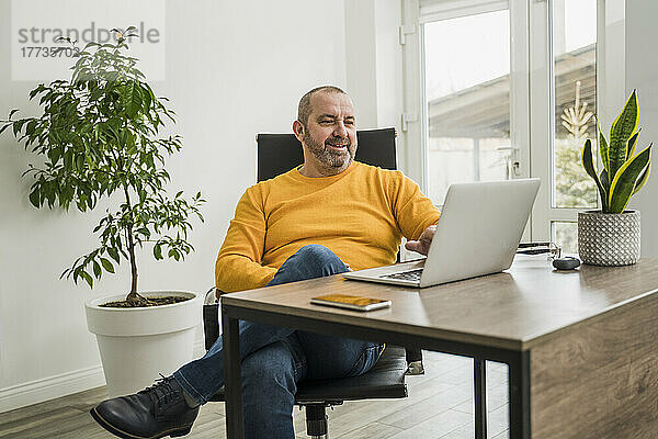 Reifer Geschäftsmann bei Videoanruf über Laptop im Büro