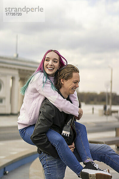 Happy man giving piggyback ride to girlfriend