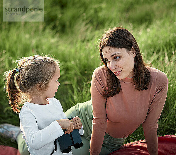 Mutter und Tochter unterhalten sich beim Picknick im Feld