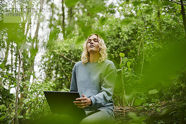Junger Freiberufler entspannt sich in der Natur und benutzt Laptop