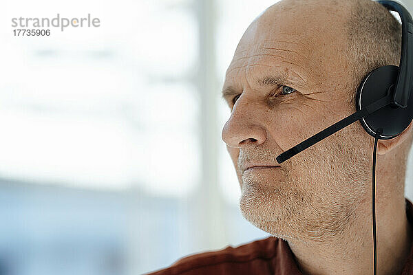 Senior businessman wearing headset in office