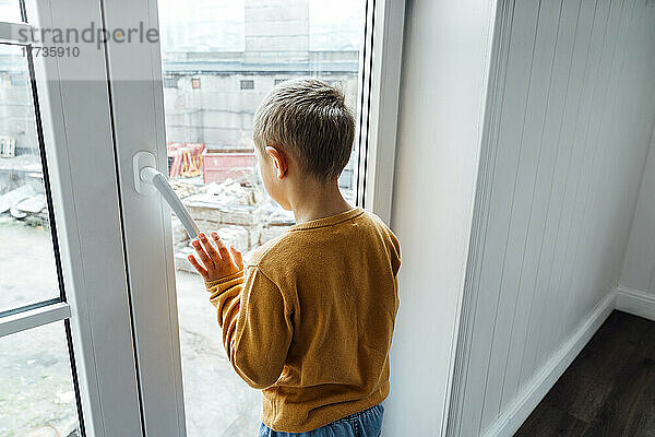 Junge schaut zu Hause durch Glasfenster