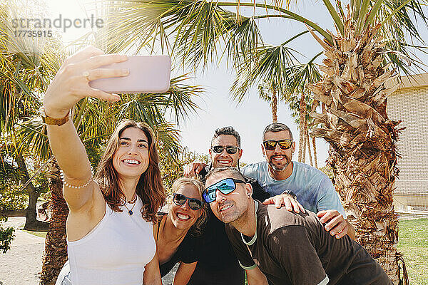 Lächelnde junge Frau mit Freunden  die ein Selfie per Smartphone machen