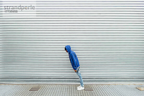 Young man leaning in front of shutter
