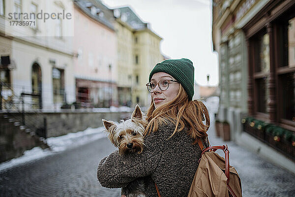 Frau mit Rucksack und Hund in der Stadt