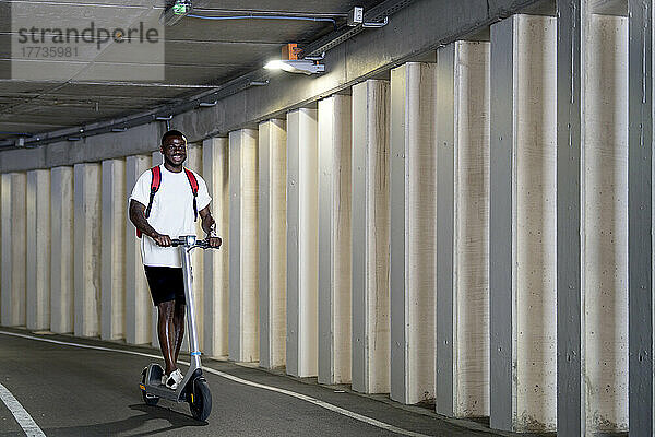 Junger Mann fährt Elektroroller im Tunnel