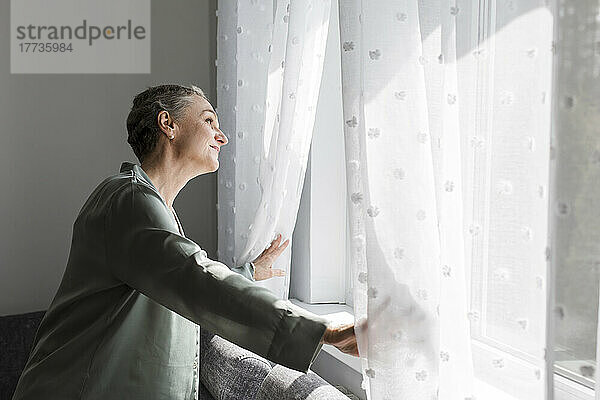 Reife Frau zu Hause  die aus dem Fenster schaut