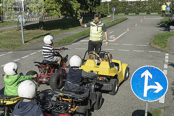 Trainer unterrichtet Kinder  die auf Quads sitzen  bei einem Renntraining zur Verkehrserziehung