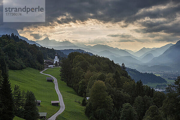 Deutschland  Bayern  Wamberg  Wolken über einer kleinen Straße  die zu einem abgelegenen Dorf im Wettersteingebirge führt