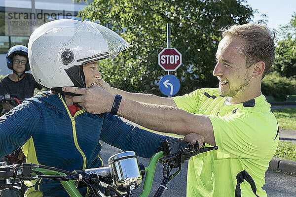 Trainer passt Schutzhelm eines Jungen auf Quad an