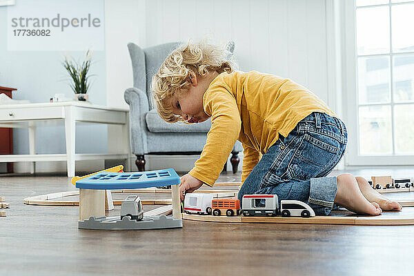 Blonder Junge spielt zu Hause mit Spielzeugeisenbahn