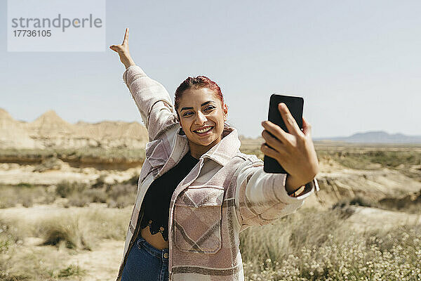 Glückliche Frau  die an einem sonnigen Tag ein Selfie mit dem Handy macht