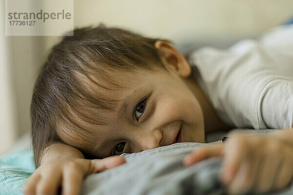Smiling boy lying on bed at home