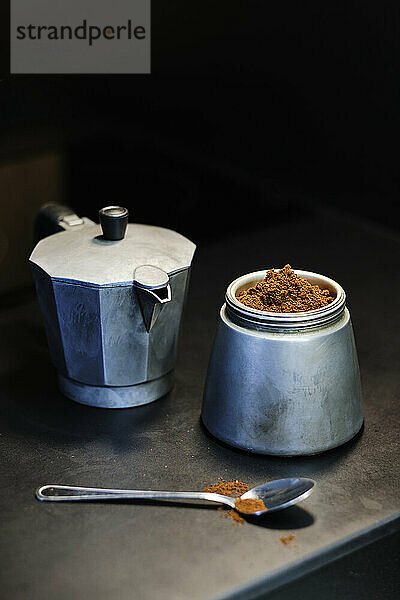 Moka pot and coffee powder in jar on table
