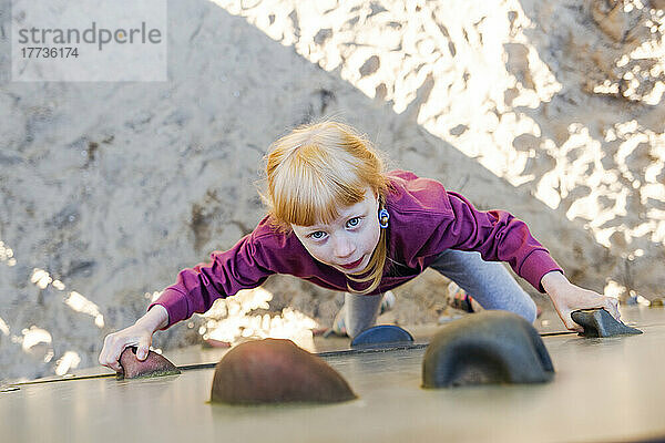 Girl with red hair climbing wall at playground