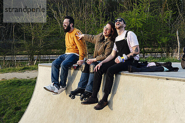 Glückliche Freunde  die es genießen  auf der Rampe im Skatepark zu sitzen