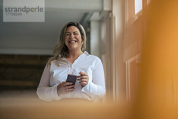 Happy businesswoman with mobile phone in office