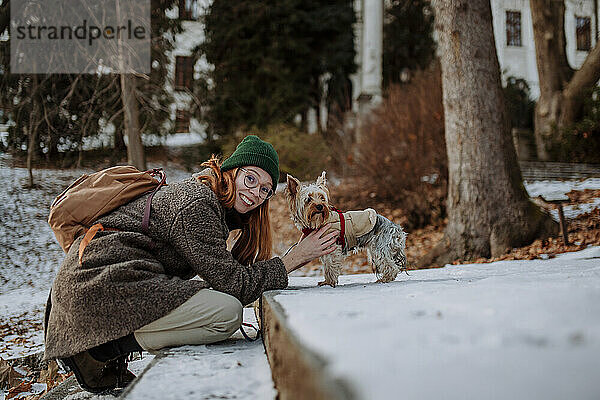 Glückliche Frau mit Hund  der sich auf Stufen lehnt