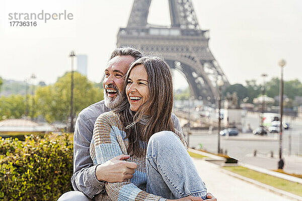 Fröhliches älteres Paar sitzt zusammen vor dem Eiffelturm  Paris  Frankreich