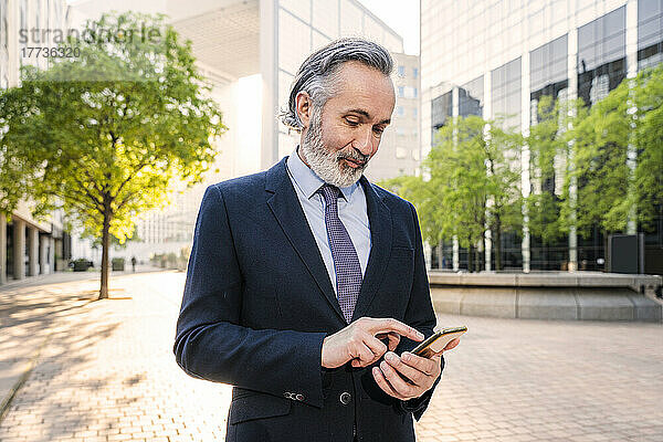 Reifer Geschäftsmann nutzt Smartphone im Büropark