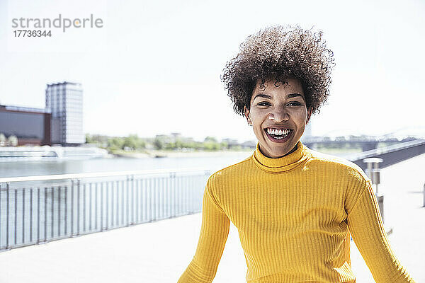 Cheerful woman laughing at promenade on sunny day