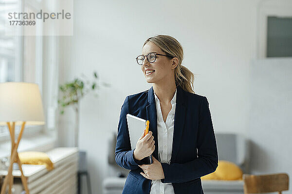 Lächelnde schöne Geschäftsfrau mit Tablet-PC im Büro
