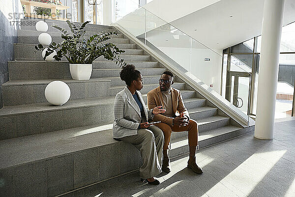 Geschäftsmann und Geschäftsfrau sitzen auf der Treppe und diskutieren im modernen Büro