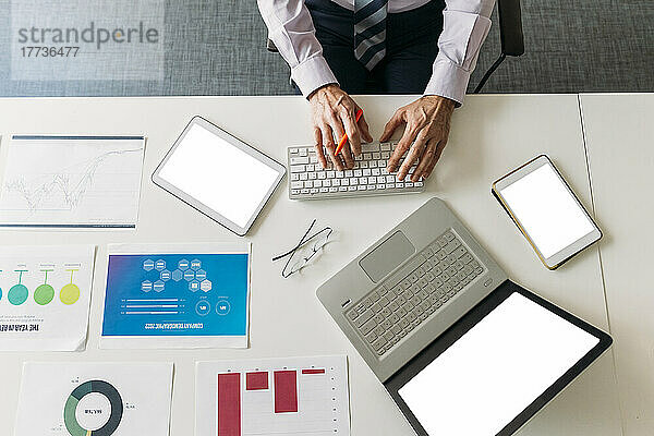 Hands of businessman typing on keyboard at desk in office
