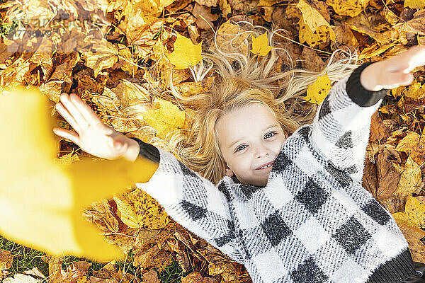 Playful girl lying on autumn leaves at park