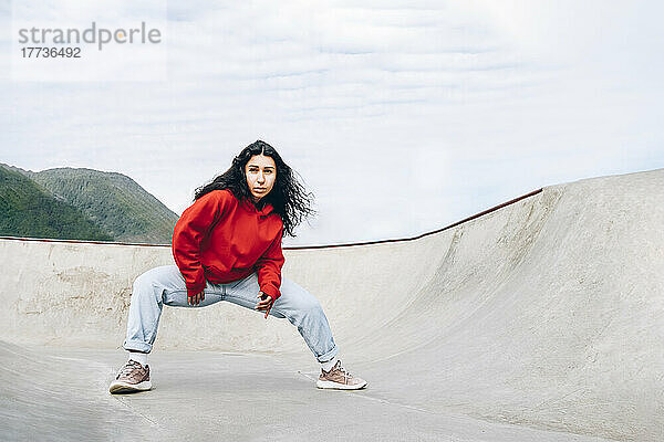 Frau mit schwarzen Haaren tanzt im Skateboardpark