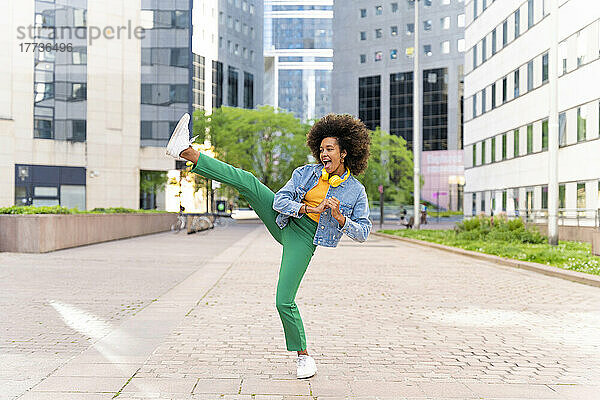 Glückliche Frau mit Afro-Frisur tritt auf Fußweg