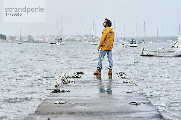 Nachdenklicher Mann steht auf einem Steg vor dem Meer
