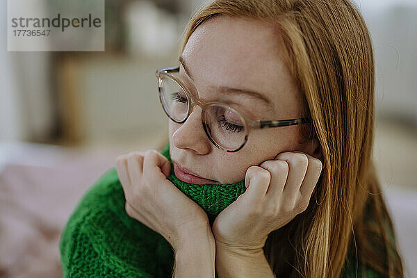 Frau trägt grünen Pullover mit geschlossenen Augen zu Hause