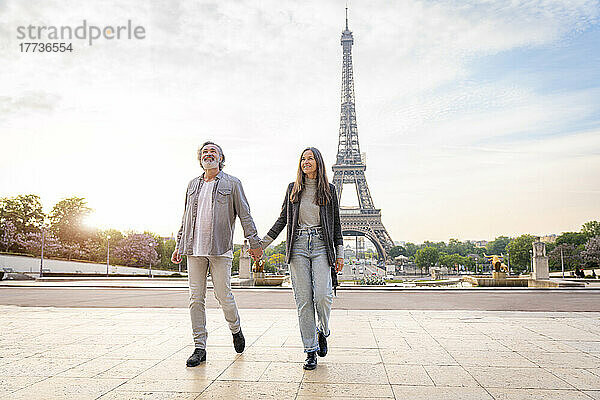 Glückliches älteres Paar hält Händchen und geht vor dem Eiffelturm  Paris  Frankreich