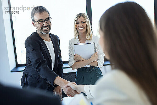 Happy businessman greeting businesswoman in office