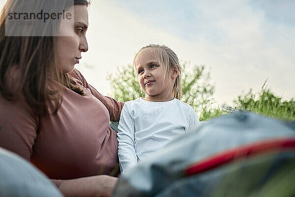 Mother talking to daughter on picnic in field