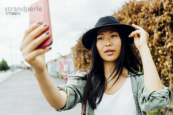 Schöne junge Frau mit Hut macht ein Selfie mit dem Smartphone