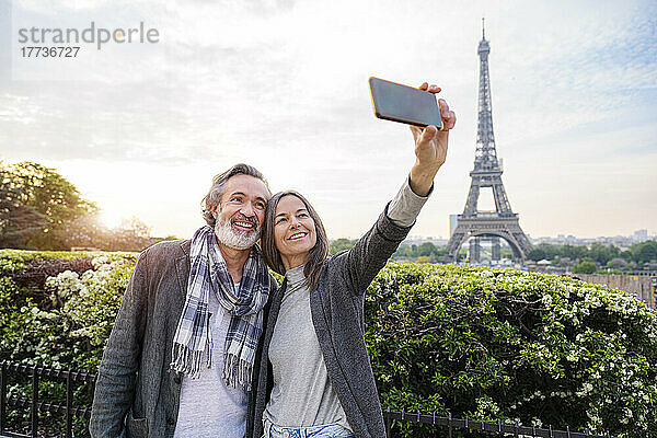 Glückliche Frau macht ein Selfie mit einem Mann per Smartphone vor dem Eiffelturm  Paris  Frankreich