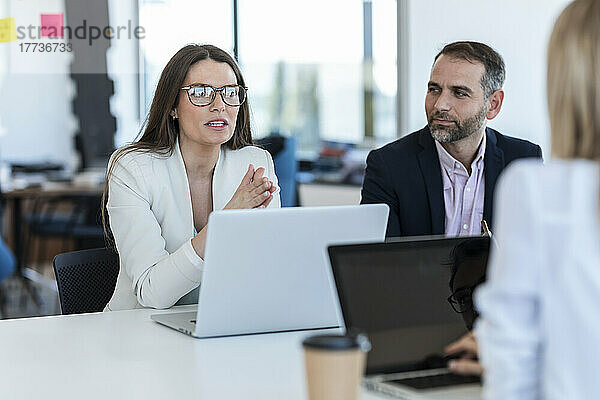 Geschäftsfrau mit Brille diskutiert Strategie mit Kollegen im Büro