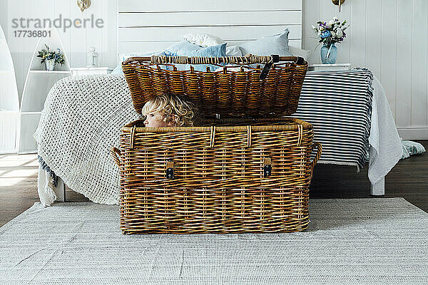 Boy hiding in wicker basket at home