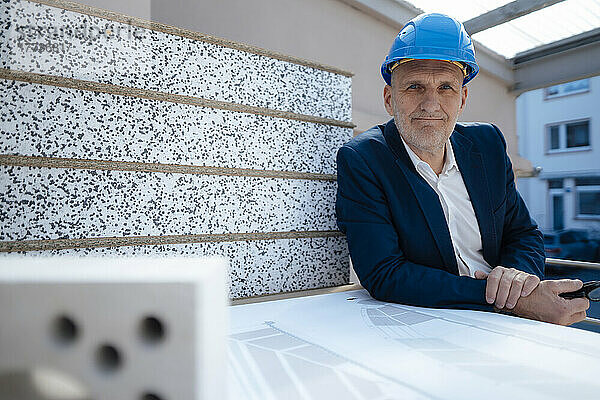 Geschäftsmann trägt Schutzhelm nach Bauplan auf der Baustelle