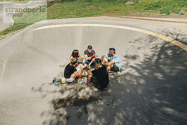 Freunde sitzen auf der Rampe und unterhalten sich im Skateboardpark