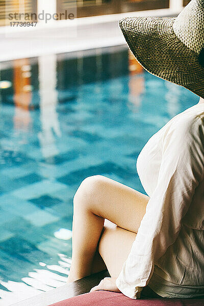 Junge Frau sitzt am Pool