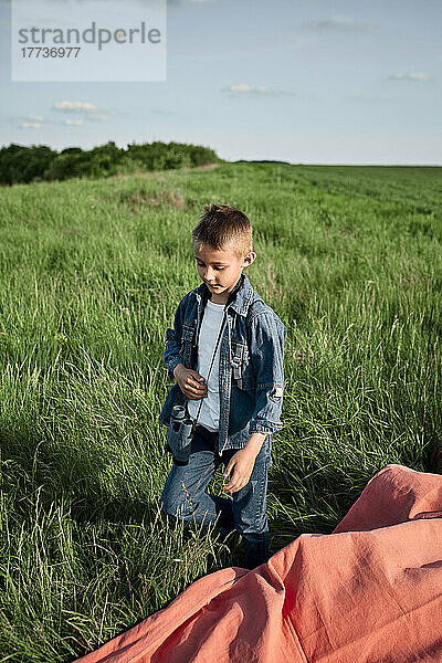 Junge mit Fernglas spaziert am Wochenende auf landwirtschaftlichem Feld
