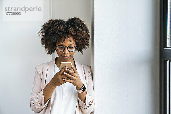 Frau benutzt Smartphone an weißer Wand am Arbeitsplatz