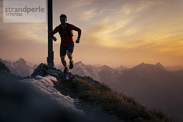 Wanderer läuft bei Sonnenuntergang auf den Gipfel des Sauling-Berggipfels