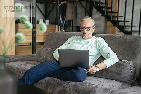 Geschäftsmann benutzt Laptop auf Sofa zu Hause