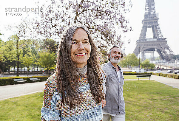 Lächelnde reife Frau mit Mann steht im Park vor dem Eiffelturm  Paris  Frankreich