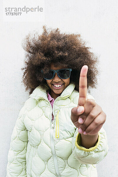 Smiling girl with sunglasses showing index finger